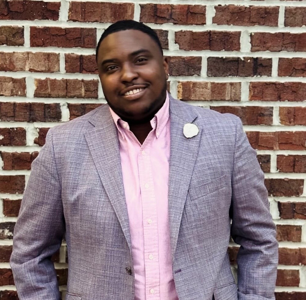 Dr. Gabriel Lockett smiling in front of a brick wall